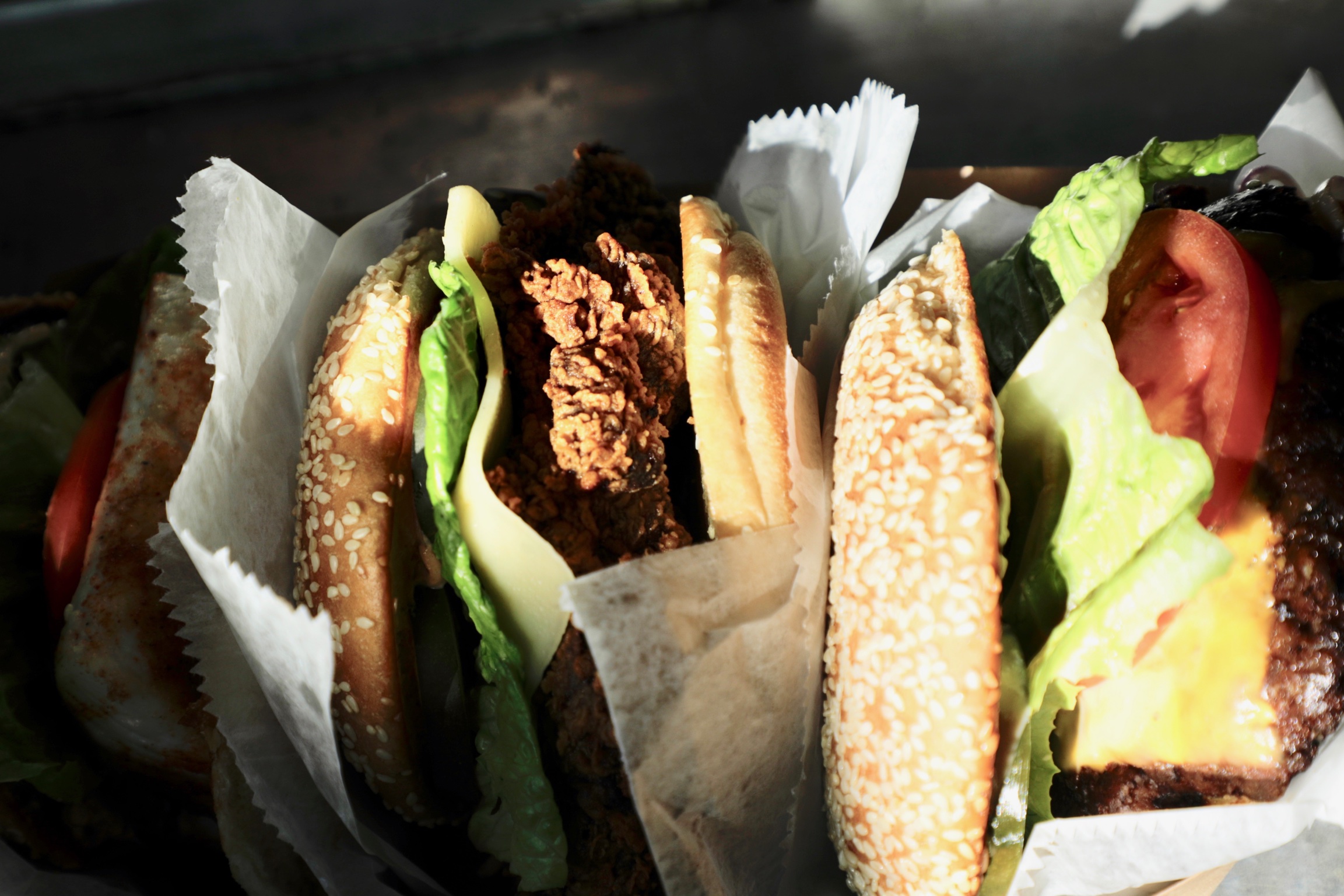 Two fried chicken sandwiches wrapped in paper, ready for pickup