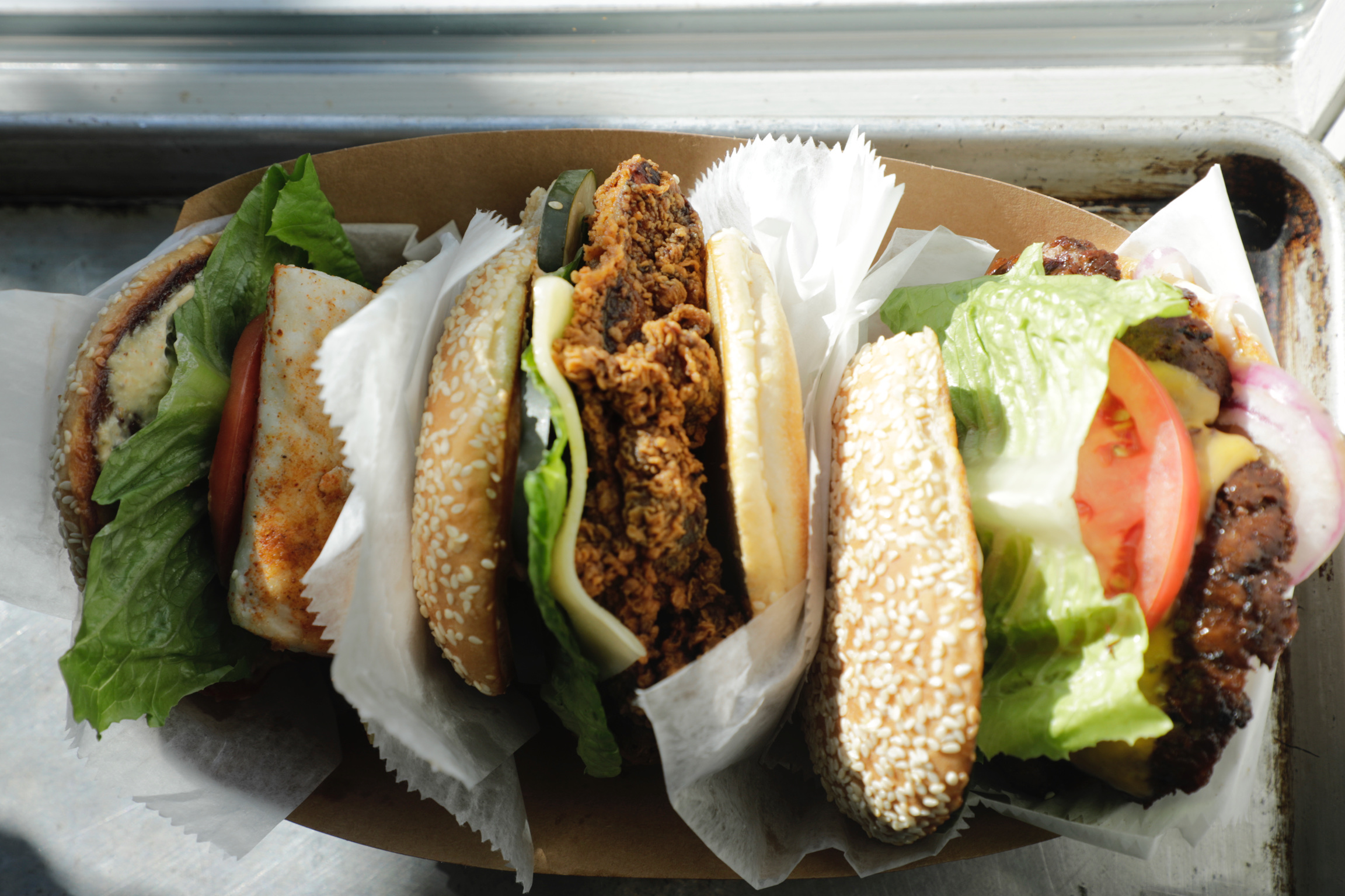 Two crispy sandwiches in paper wrap with lettuce on a sesame bun