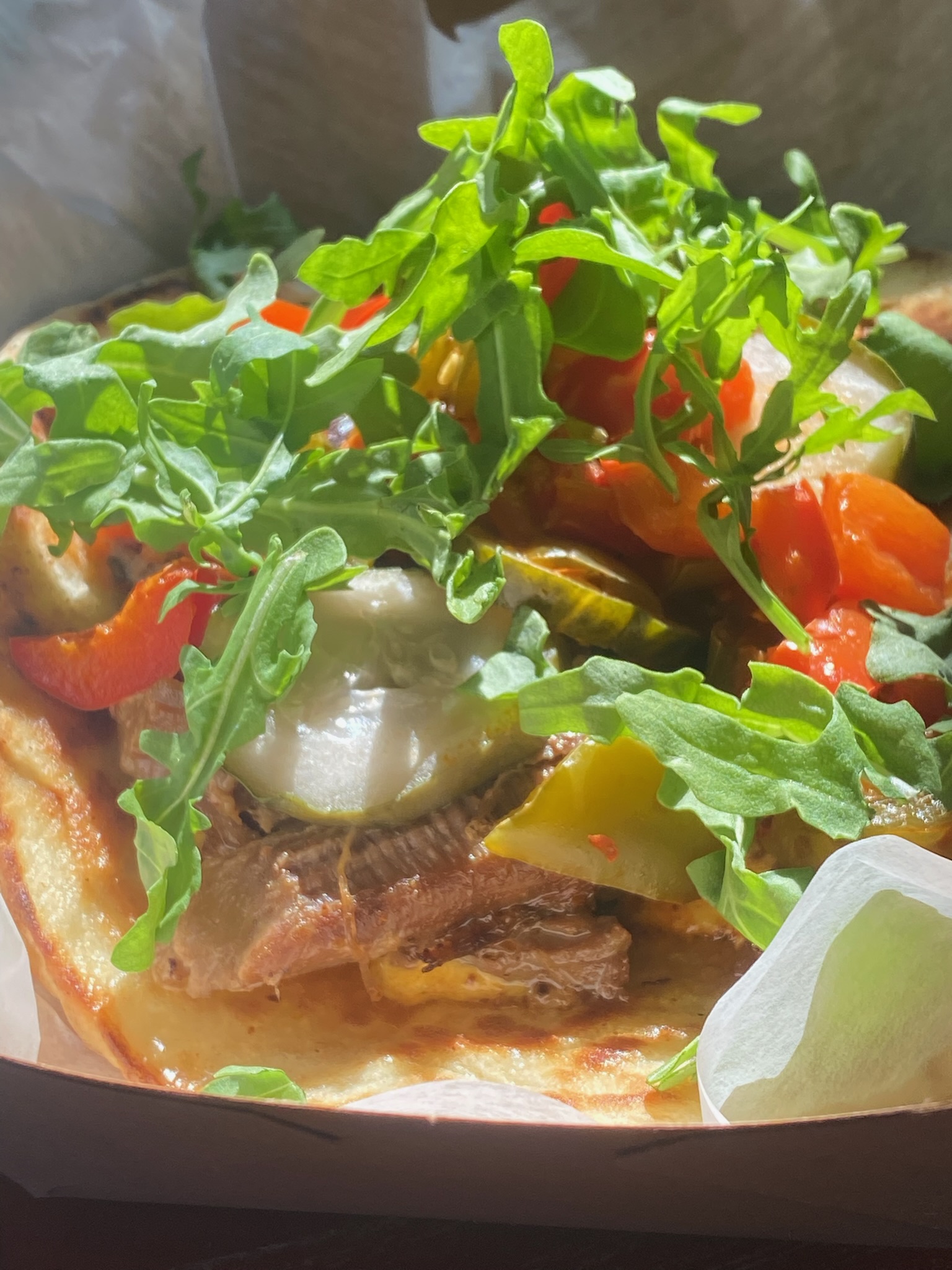 Pulled lamb on pita topped with arugula, roasted peppers and yogurt sauce