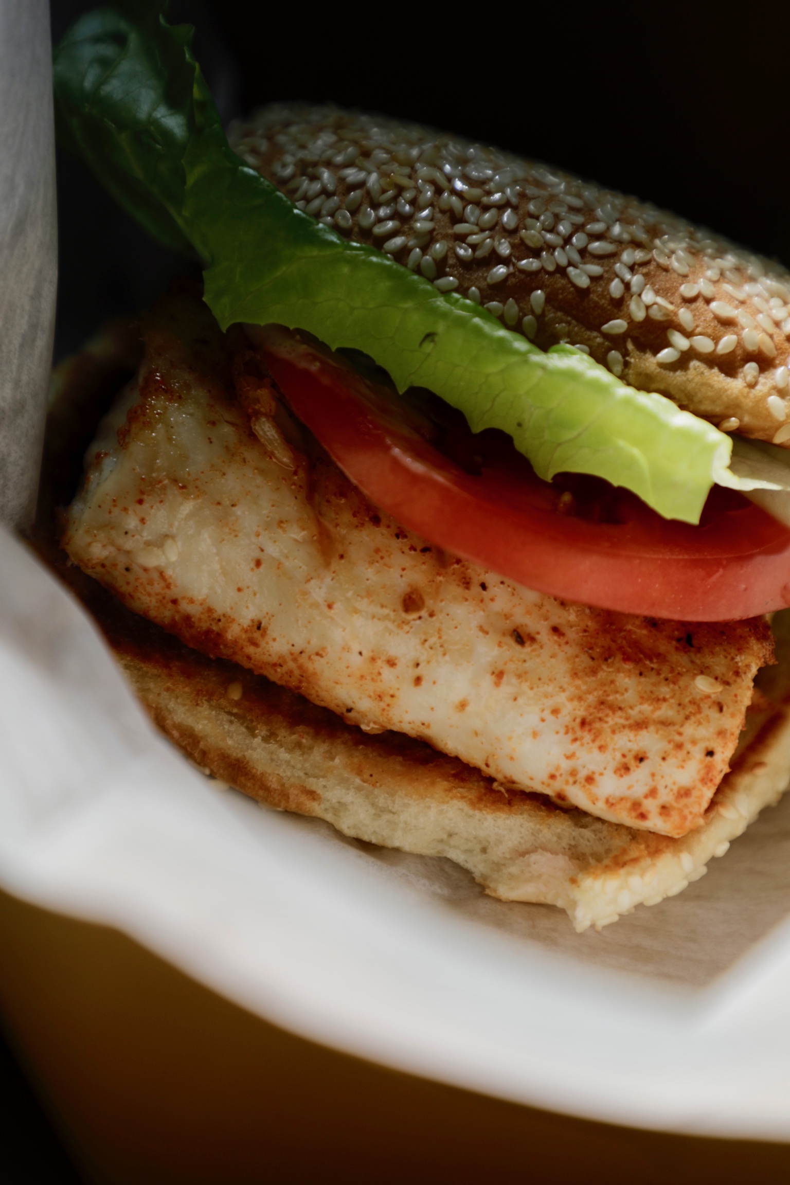 Close-up of a fish sandwich with tomato and crisp lettuce