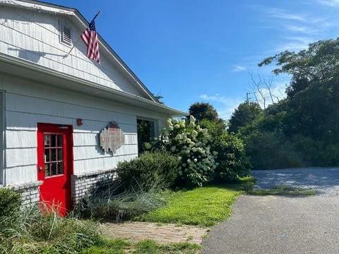 The North Fork Shack — weathered clapboard building with a red door and American flag